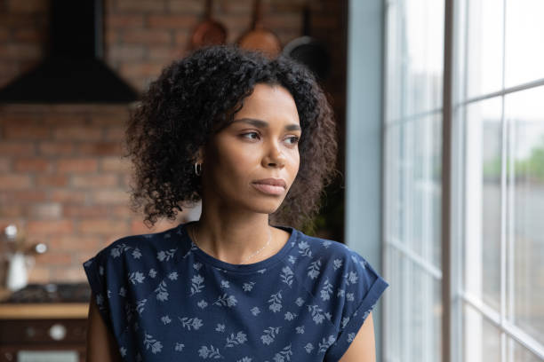 Close up upset African American woman looking to aside Close up upset African American woman looking to aside out window, standing at home, serious thoughtful young female lost in thoughts, thinking about problem, worried by break up with boyfriend soul searching stock pictures, royalty-free photos & images