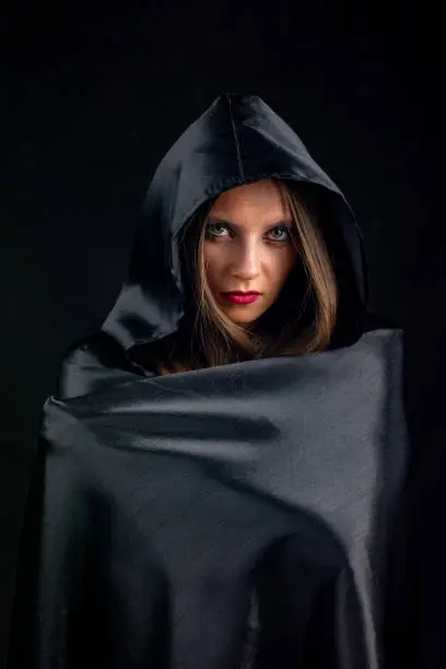 Photo of Portrait of a girl in a silk black cloak