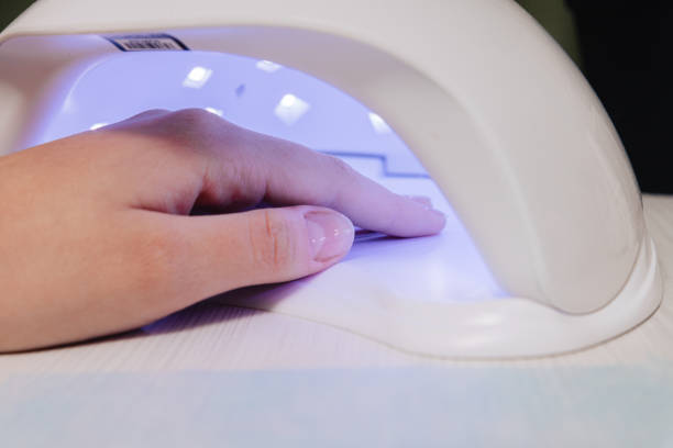 istock Manicure process. Drying nails in a device with ultraviolet lamps. 1303922228