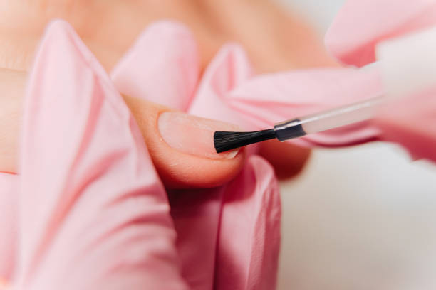 istock Manicure process. The master paints the nails with transparent varnish 1303922318