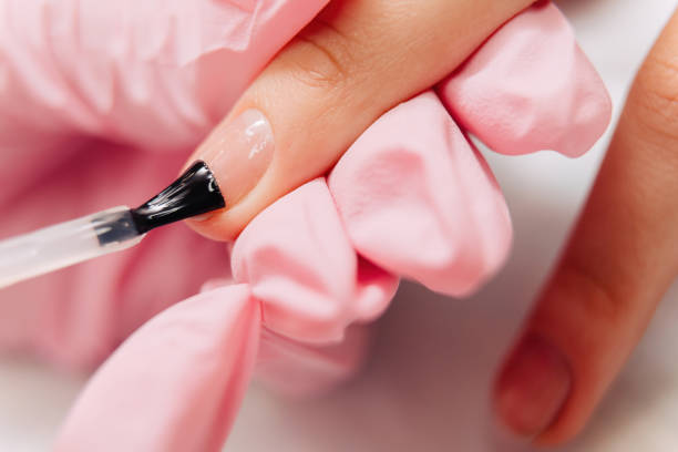 istock Manicure process. The master paints the nails with transparent varnish 1303922367