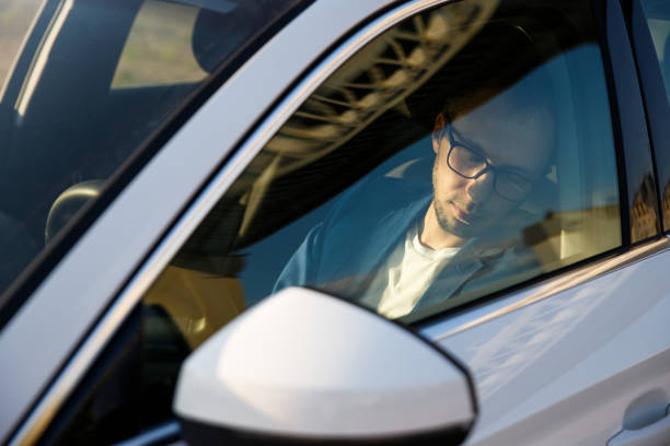 istock Tired business man falling asleep sitting inside her car seen through windshield 1303924056