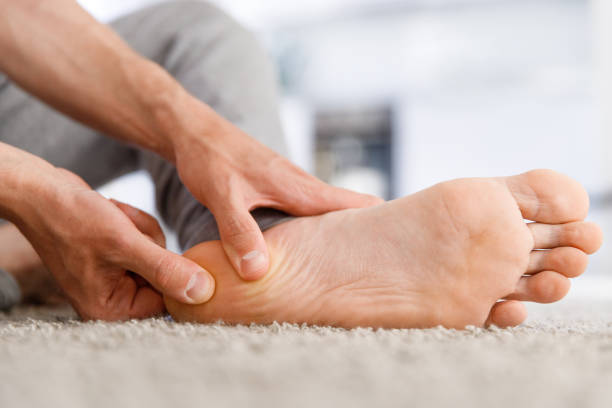 Man hands giving foot massage to yourself after a long walk Man hands giving foot massage to yourself after a long walk, suffering from pain in heel spur, close up, indoors. Flat feet, leg fatigue, plantar fasciitis, foot stock pictures, royalty-free photos & images
