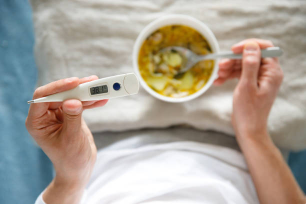 건강한 치킨 수프를 먹고 있는 남성은 독감병에 맞서 온도계를 들고 - soup chicken soup chicken noodle soup food 뉴스 사진 이미지