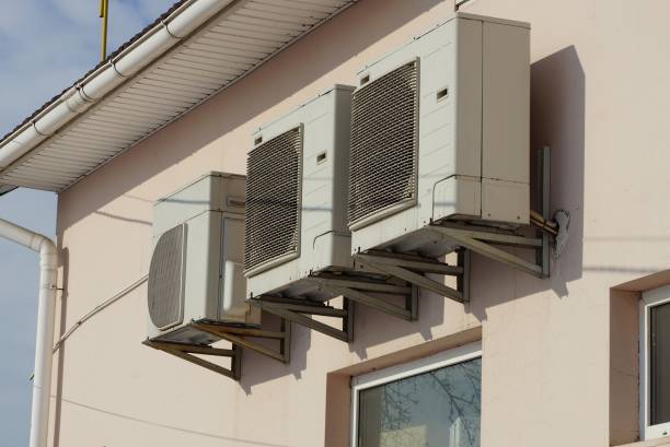 istock three large gray air conditioners on a brown wall 1303926226