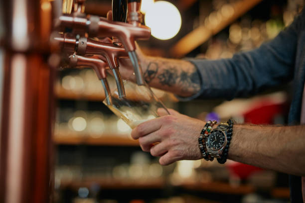 istock A bartender pouring beer into the pint glass while standing in bar. 1303927676