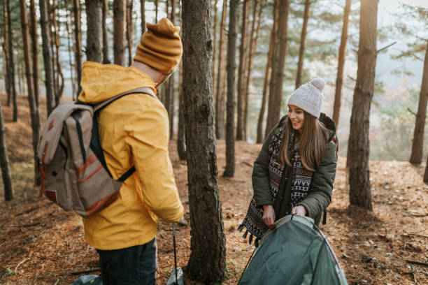 Couple is assembling tent in the woods and having fun on a sunny day