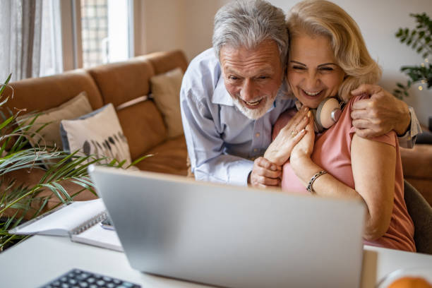 istock Happy senior couple at home, using laptop 1303928760