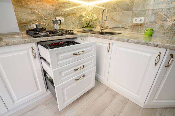 istock Drawers pulled out at modern classic white kitchen furniture 1303933337