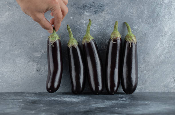 istock Male hand taking aubergine from row 1303935455