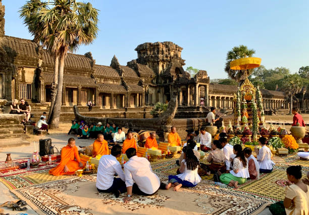 Woman with backpack and hat stands in the Southern Library window of Angkor Wat, gazing at the ancient temple during sunrise. Concept for adventure, reflection, and cultural travel.
