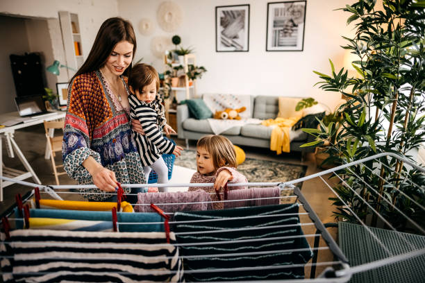istock Mother and daughter putting laundry on clothes rack 1303942395