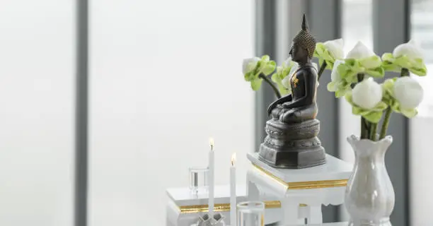 Photo of religious background of metal buddha statue on altar shelf at home for buddhist people worship and chanting