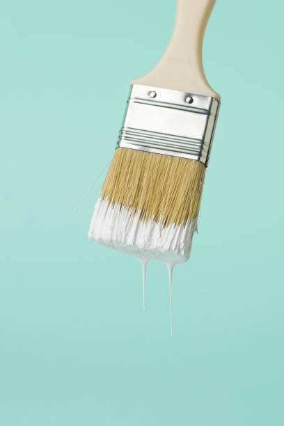 istock Brush with dripping white paint on a blue background. 1303957593