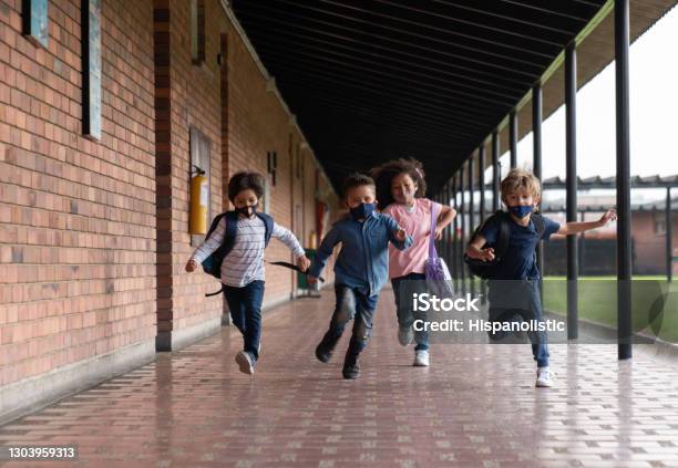 Children Running At The School While Wearing Facemasks Stock Photo - Download Image Now