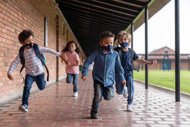 istock Kids running at the school while wearing facemasks 1303959319
