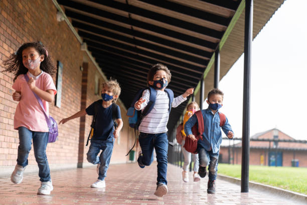 istock Kids running and looking very excited to be back at school while wearing facemasks 1303959366