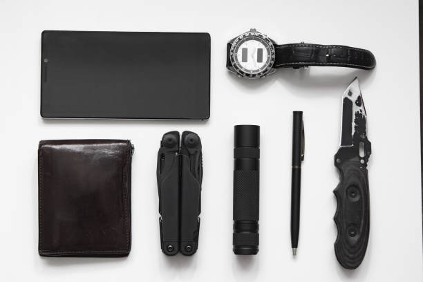 vista dall'alto del trasporto quotidiano (edc) oggetti per uomini di colore nero su sfondo bianco - torcia elettrica, orologio, multitool multiattrezzamento, telefono, penna. moderno set da città. concetto minimale. - tactical flashlight foto e immagini stock