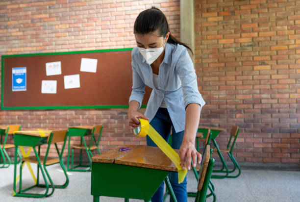 istock Teacher implementing guidelines of social distancing in a school classroom 1303960338