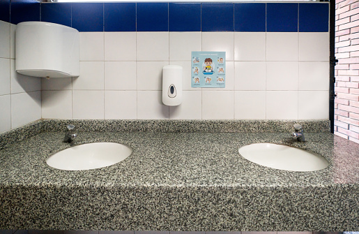New paper towel dispenser hanging on wall near mirror in bathroom. Modern bathroom interior details