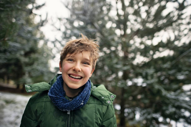 Portrait of little boy hiking on winter day. They boy is wearing green jacket and is laughing.\nShot with Canon R5