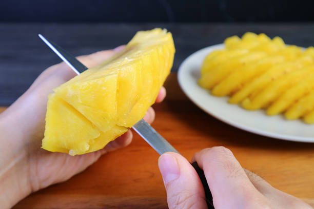 Man cutting fresh ripe pineapple in pieces before serving