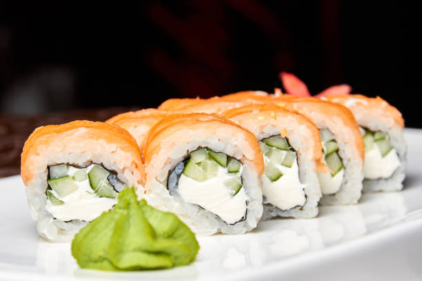 istock Rolls with salmon and cucumber, cheese and wasabi on a white plate 1303975305