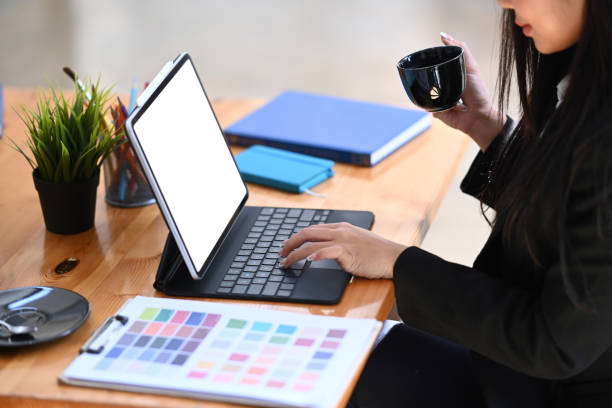 istock Young female graphic designer working on digital tablet and drinking hot coffee. 1303975307