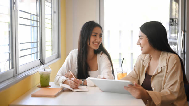 istock Two young women using digital tablet and discussing their small business in cafe. 1303975324