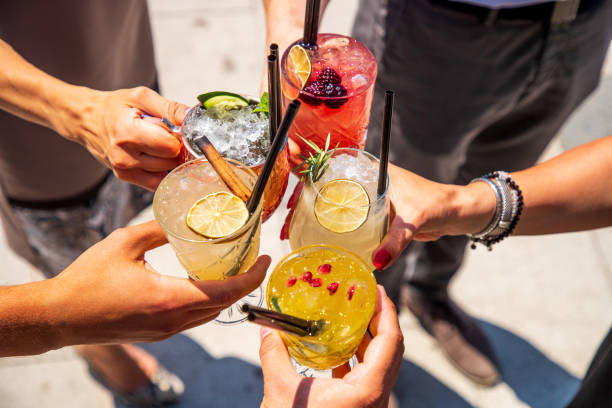 Five hands holding coctails on ice in celebratory toast