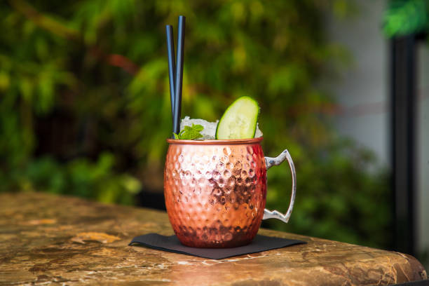 Copper jug of cocktail on crushed ice with cucumber slice and mint leaf