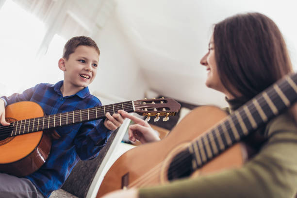 istock Brother and sister playing guitar at home and having fun. 1303977648
