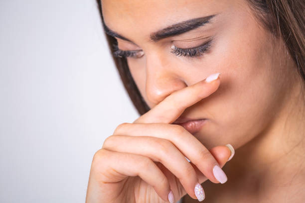 istock Young woman touches her nose - Concept showing avoid touch face to protect and prevent form covid-19, sars cov 2 or coronavirus outbreak or spreading. 1303979014