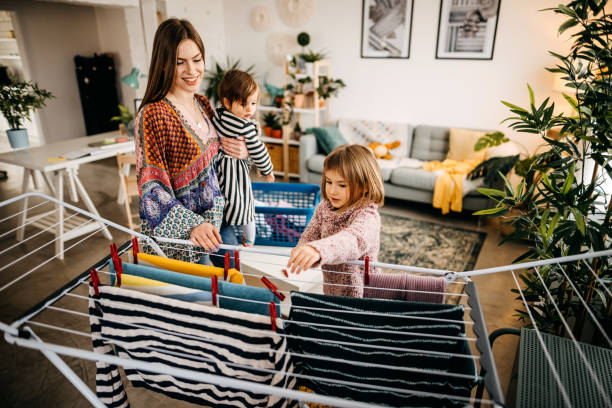 istock Mother and daughter putting laundry on clothes rack 1303979921