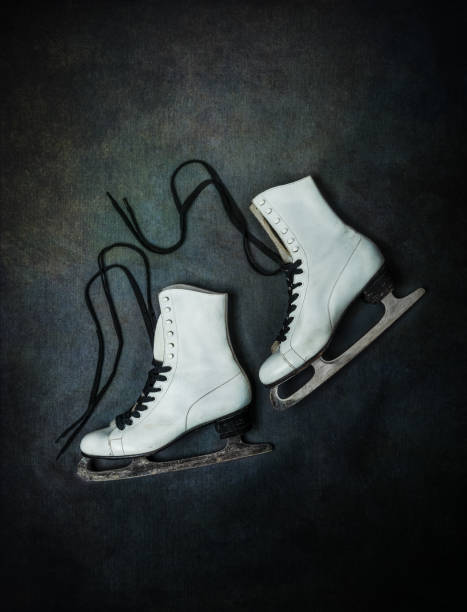 istock Old white ice skates with black laces on dark rustic background 1303979943