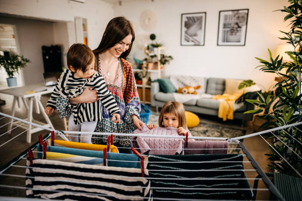 istock Mother and daughter putting laundry on clothes rack 1303979982
