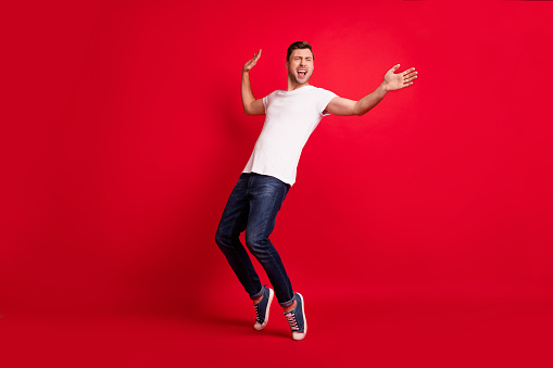 Full body portrait of excited handsome person look empty space partying isolated on maroon color background.