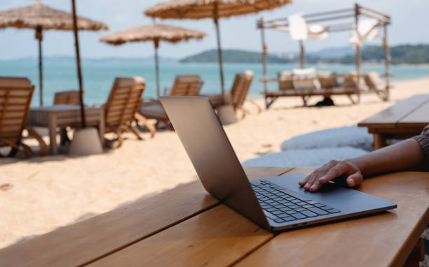 istock a woman working and touching on laptop touchpad on the beach 1303987184