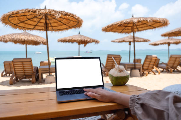istock a woman using and touching on laptop touchpad with blank desktop screen while sitting on the beach 1303987223