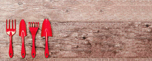 istock Web banner with vivid red gardening tools on the wooden surface. Background with copy space for advertisement text. Gardening equipment 1303987663