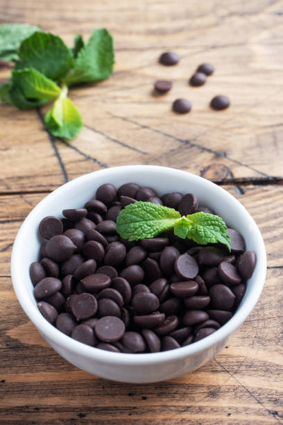istock Chocolate drops for decorating desserts in a plate with mint on a wooden background. 1303990377