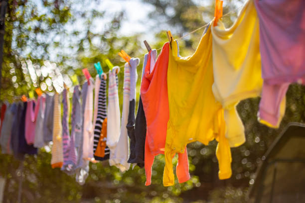 Baby cute clothes hanging on the clothesline outdoor. Child laundry hanging on line in garden on green background. Baby accessories. stock photo