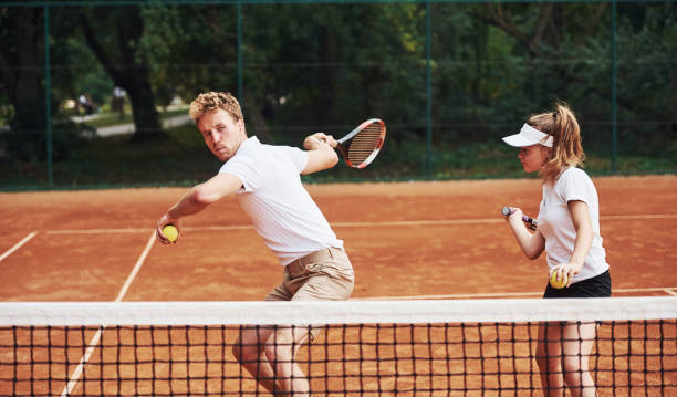 deux personnes dans l’uniforme de sport joue au tennis ensemble sur le court - tennis club photos et images de collection