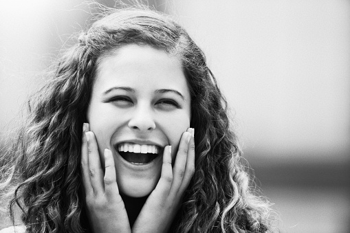 Happiness is written on the face of a young woman with striking long curly hair.
