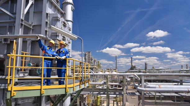 trabajo en equipo: grupo de trabajadores industriales en una refinería - equipos de procesamiento de petróleo y maquinaria - industria petrolera fotografías e imágenes de stock