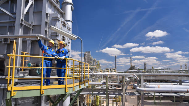 lavoro di squadra: gruppo di lavoratori industriali in una raffineria - attrezzature e macchinari per la lavorazione del petrolio - raffineria foto e immagini stock