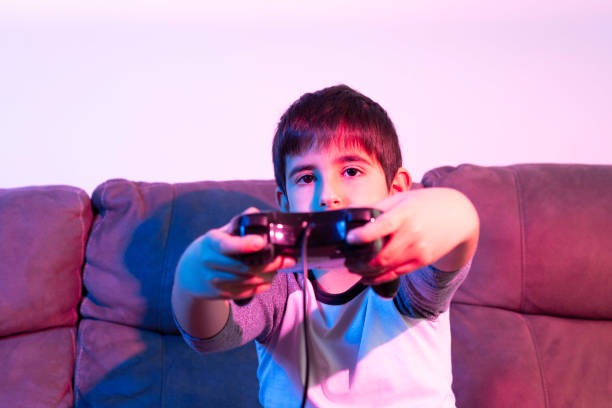 istock Boy plays video games from the couch under red and blue lights 1304001408