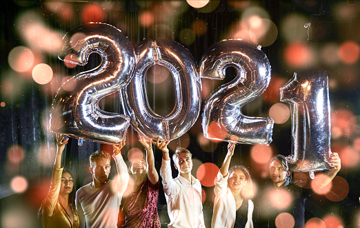 Positive young people holds balloons with new 2021 year and celebrating.