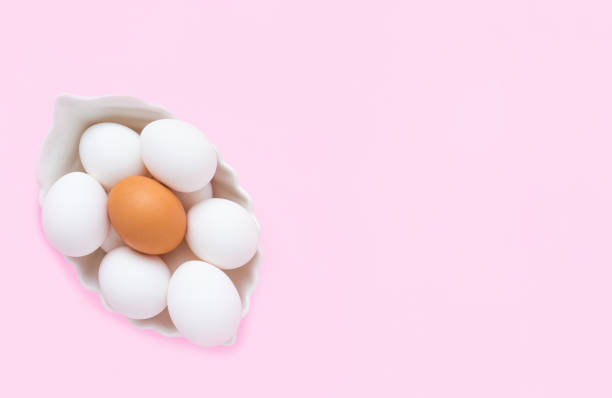 istock Many white eggs and one brown egg in a white dish on a pink background. Easter. Copy space, top view. 1304003018