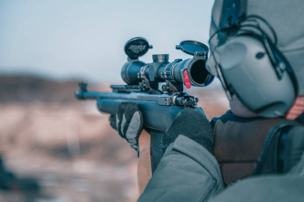 istock Shooter with a rifle. Man shoots a rifle, rear view, selective focus on optical sight, close-up 1304003834